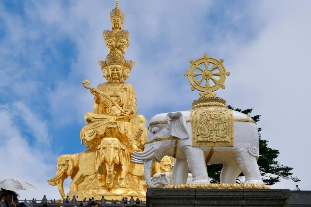 Stunning golden Buddha statue and white elephant at Mount Emei temple, highlighting Asian spirituality and art.
